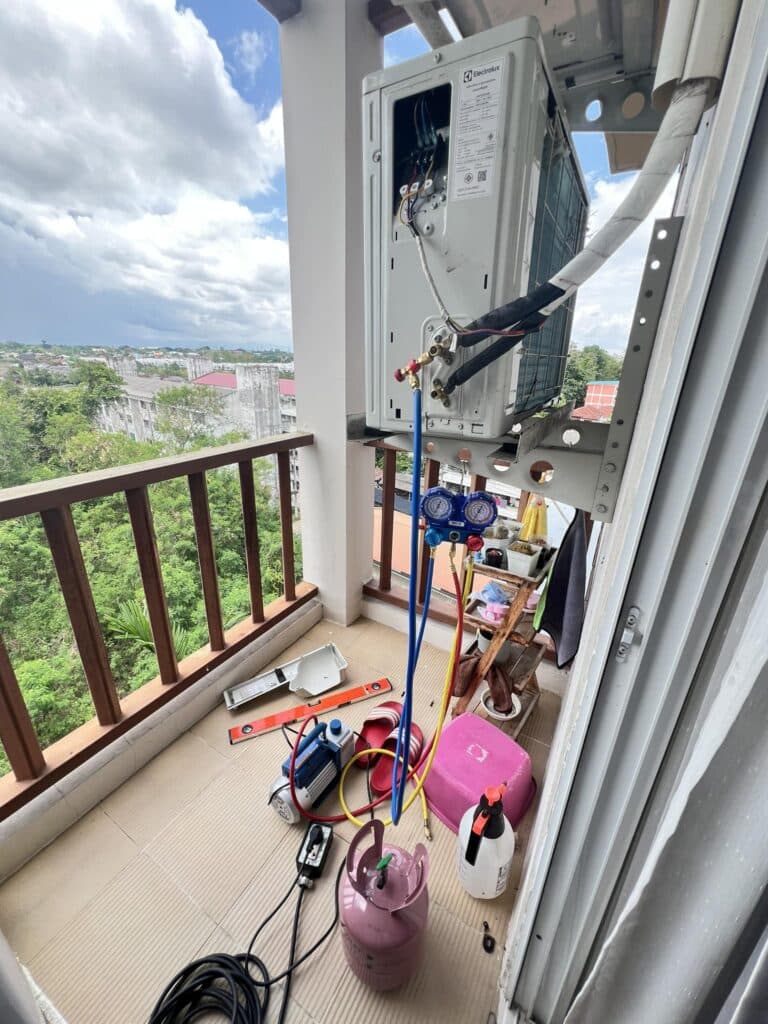 Arm cleaning a wall-mounted air conditioner at a customer's home in Chiang Mai