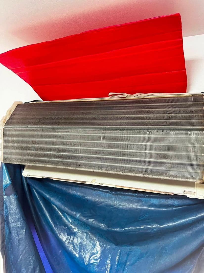 แผงคอยล์เปลือยวางบนผ้าใบสีน้ำเงินคู่กับรางน้ำพลาสติกสีแดงที่เตรียมไว้