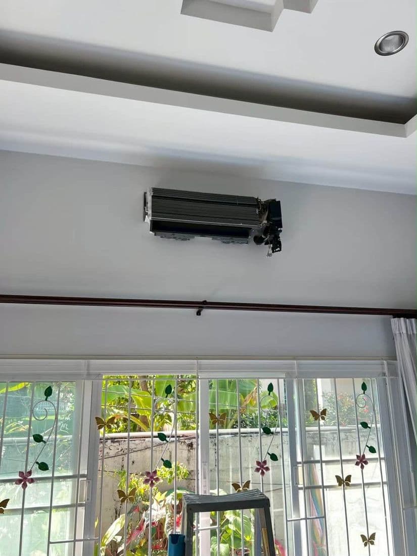 ตัวเครื่องแอร์ที่ถอดฝาครอบออกแล้วยังติดอยู่บนผนัง เห็นโครงสีดำด้านใน