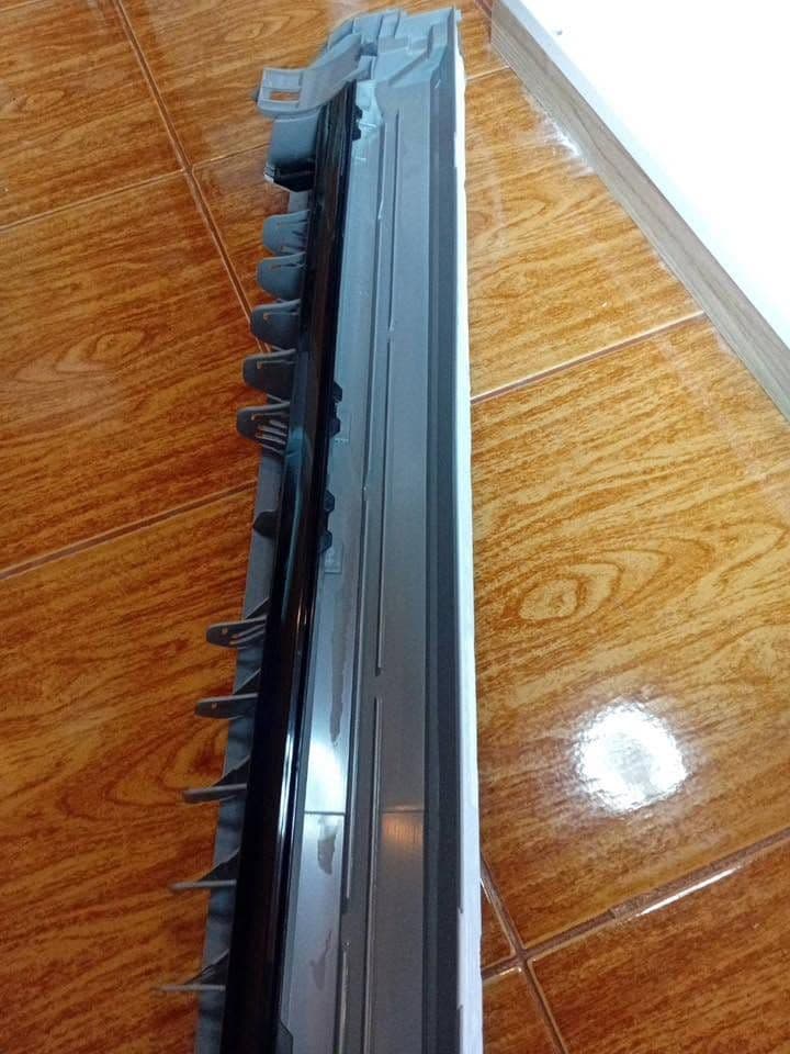 ตัวเครื่องแอร์วางคว่ำบนพื้นกระเบื้องลายไม้ ถ่ายเลียบไปตามแนวสันยาว
