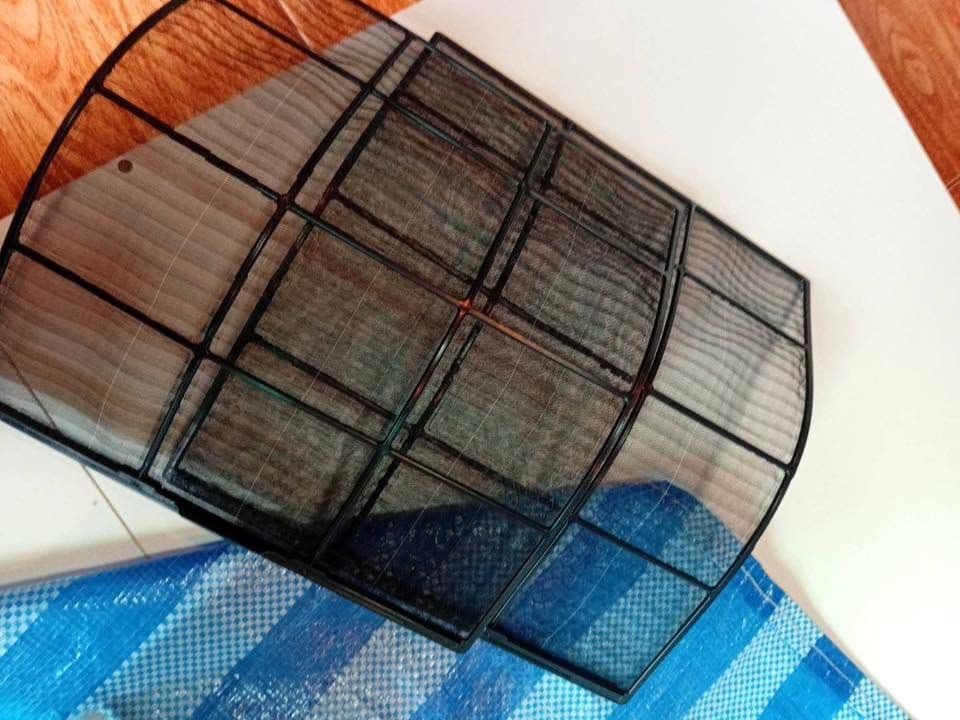 แผ่นกรองกรอบสีดำวางอยู่บนผ้าใบสีน้ำเงินหลังฉีดล้างจนสะอาดแล้ว