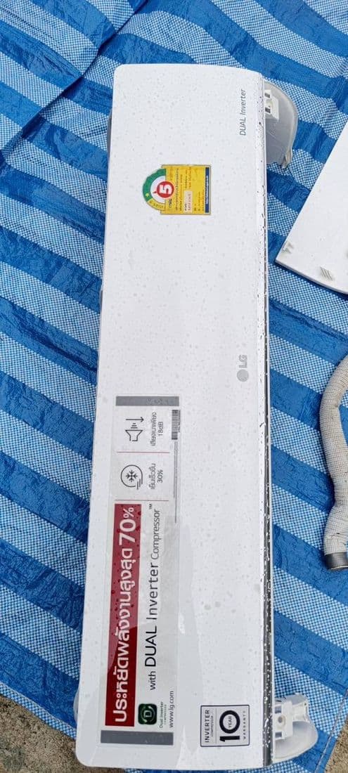 ฝาครอบแอร์ที่ยังมีสติกเกอร์ฉลากติดอยู่ วางคว่ำบนผ้าใบสีน้ำเงินกลางแจ้ง