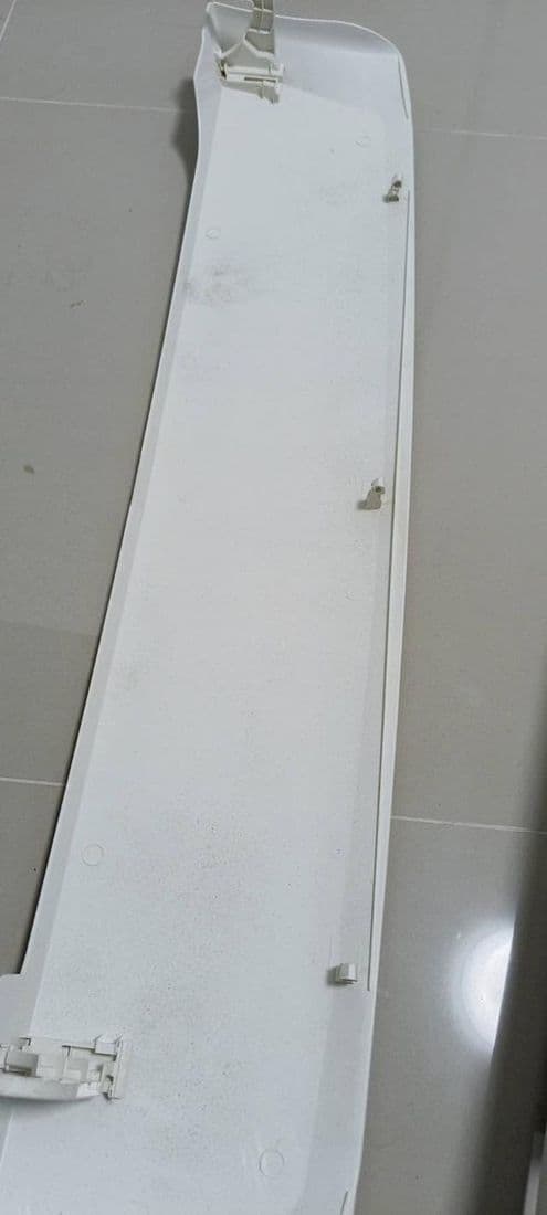 ฝาครอบแอร์สีขาววางพิงผนังกระเบื้อง ถ่ายไล่ไปตามแนวยาวของชิ้นงาน