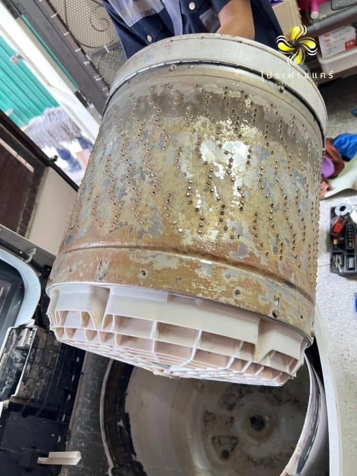 ยกถังซักเปื้อนคราบน้ำตาลออกจากตัวเครื่องกลางแจ้ง เห็นฐานพลาสติกสีขาวติดอยู่ก้นถัง