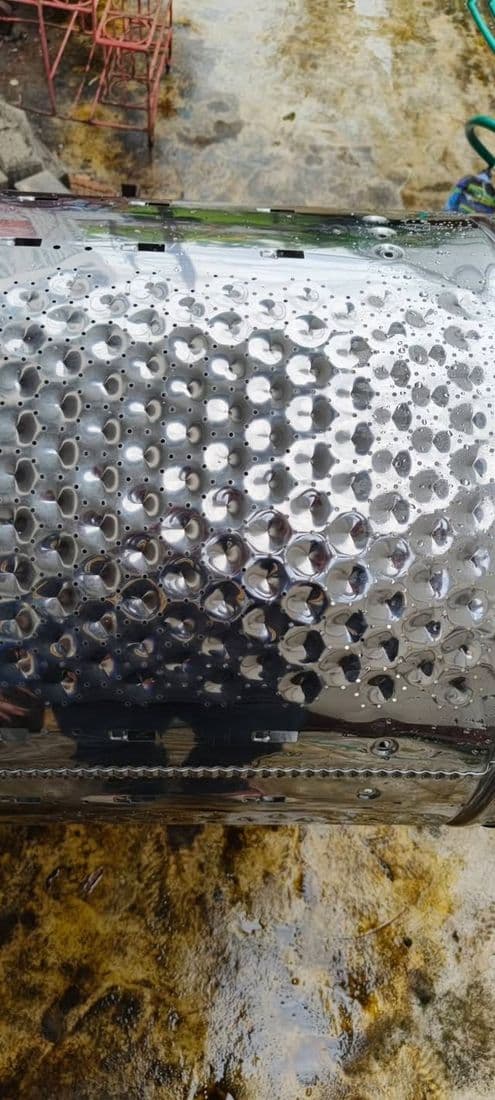 ถังซักที่ล้างแล้วเอียงพิงอยู่ เห็นรูระบายนูนเรียงเป็นแถวถี่