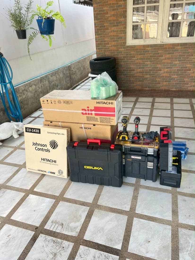 กล่องเครื่องปรับอากาศใหม่และกล่องเครื่องมือช่างวางกองรวมกันบนพื้นกระเบื้องหน้าบ้าน