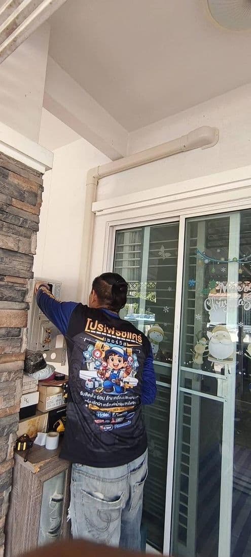 ช่างยืนติดรางครอบท่อบนผนังหินริมประตูกระจกบานเลื่อน