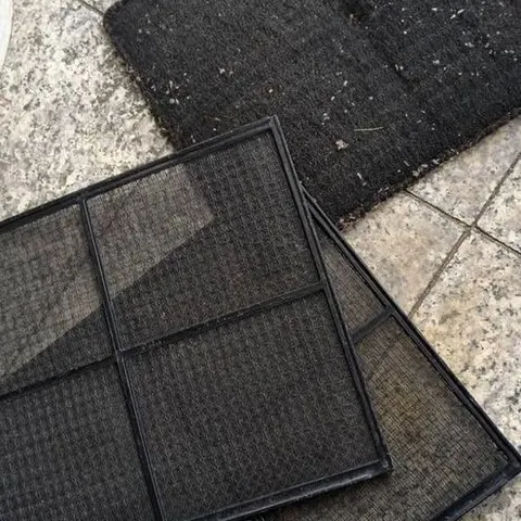 แผ่นกรองอากาศกรอบดำสามแผ่นวางเรียงบนพื้นหินขัด คราบฝุ่นจับจนตาข่ายทึบ