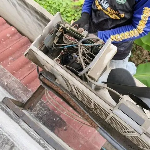 ช่างนั่งถอดชิ้นส่วนของเครื่องแอร์แขวนออกทีละชิ้นระหว่างเตรียมล้าง
