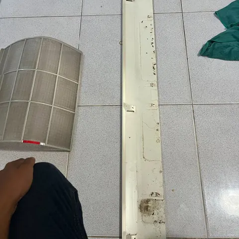 แผ่นกรองและชิ้นส่วนแนวยาววางรออยู่ ช่างเอื้อมมือหยิบขึ้นมาล้าง