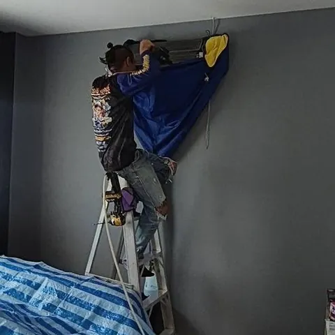 ห้องนอนที่ปูผ้ากันน้ำสีฟ้ารองไว้ใต้เครื่องปรับอากาศ ก่อนเริ่มงานล้าง