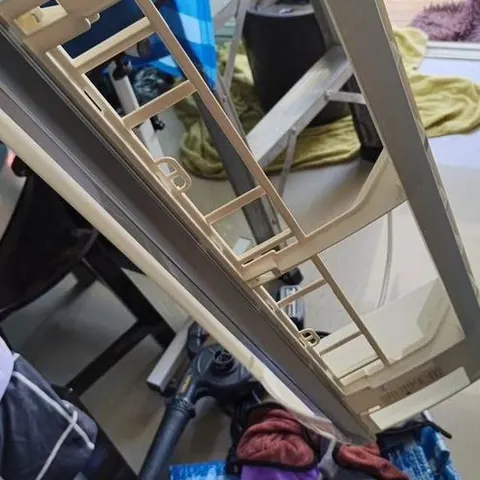 โครงหน้ากากพลาสติกยกขึ้นถือกลางห้อง เห็นช่องลมและรูยึดชัดเจน
