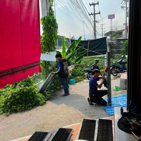ช่างสองคนช่วยกันล้างชิ้นส่วนแอร์ที่ถอดออกมาวางเรียงไว้
