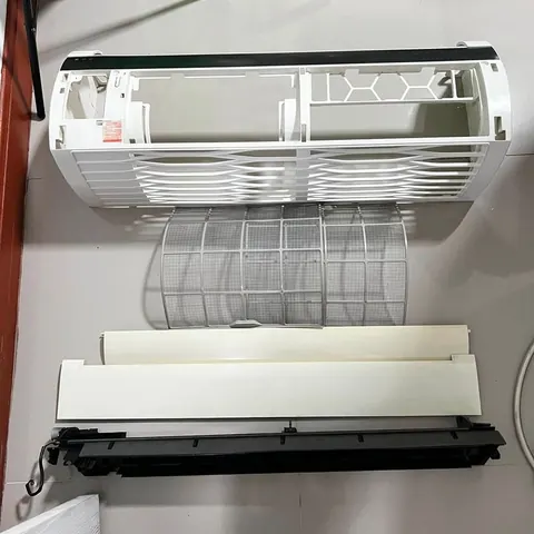 แอร์ติดผนังเปิดฝาครอบและถอดแผ่นกรองวางพิงไว้ที่ผนังสีขาวก่อนเริ่มล้าง
