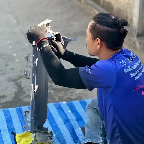 ช่างนั่งคุกเข่าถือชุดใบพัดโบลเวอร์ขึ้นตรวจดูสภาพซี่ใบพัด