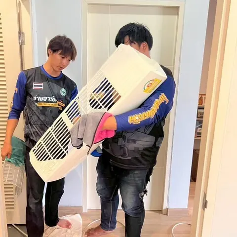 ช่างสองคนช่วยกันยกฝาครอบแอร์ที่ถอดออกมาแล้วประคองไว้
