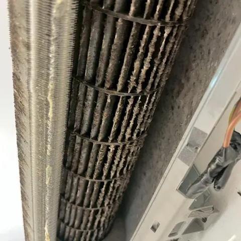 ระยะใกล้ครีบคอยล์ที่มีฝุ่นดำอุดตันแน่นเต็มแนว ถ่ายก่อนเริ่มล้าง