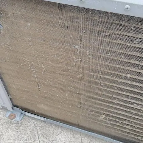 ครีบคอยล์ที่มีฝุ่นสีน้ำตาลอุดตันจนแน่นทั้งแผง ถ่ายมุมกว้างก่อนล้าง