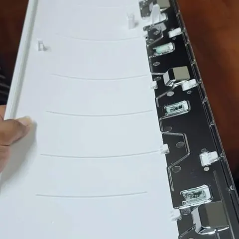 ฝาหน้าแอร์เปิดหงายให้เห็นโครงด้านในและช่องล็อก วางบนพื้นห้อง