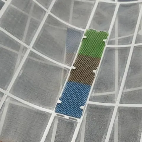 แผ่นกรองอากาศล้างสะอาดจนเห็นแถบสีด้านใน ถือขึ้นเหนือผ้าปูลายทาง