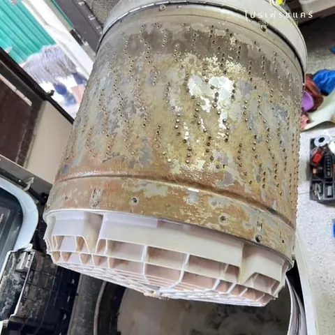 ยกถังซักที่เปื้อนคราบน้ำตาลออกจากตัวเครื่อง เห็นฐานพลาสติกสีขาวติดอยู่ก้นถัง