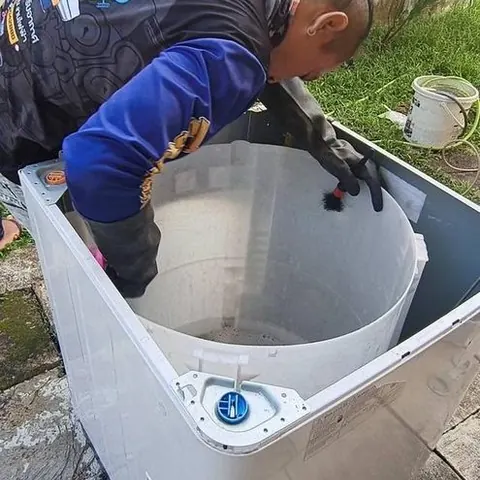 ช่างก้มล้างชิ้นส่วนถังในกะละมังพลาสติก ระหว่างขั้นตอนแช่ล้างคราบ