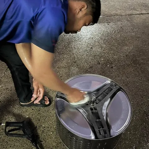 ช่างขัดด้านหลังถังซักด้วยฟองน้ำ มีหัวฉีดแรงดันเตรียมไว้ข้างตัว