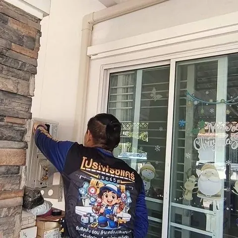 ช่างยืนติดรางครอบท่อบนผนังหินริมประตูกระจกบานเลื่อน