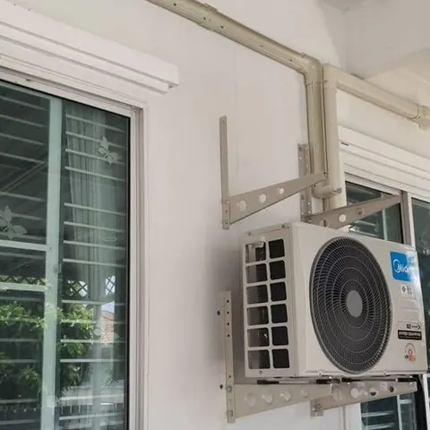 คอยล์ร้อนแขวนบนขายึดข้างหน้าต่าง มีรางครอบท่อเดินลงมาตามแนวผนัง